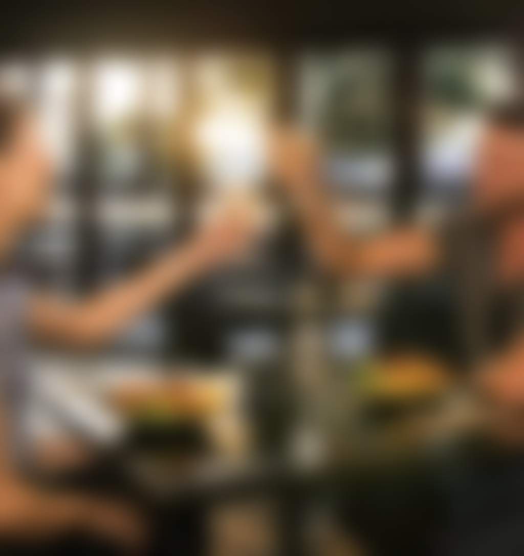 A couple at a table for two enjoying food and drinks with the sunset in the background