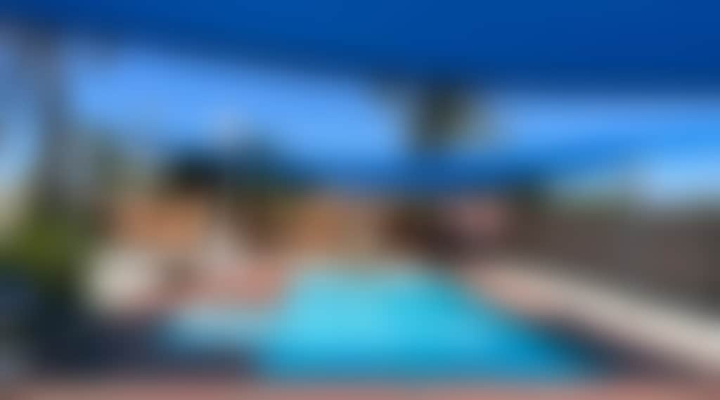 Shaded area featuring a blue pool and lounges