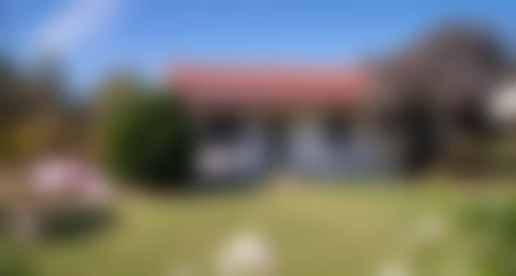 Frontal view of the cottage engulfed in greenery and surrounded by flowers
