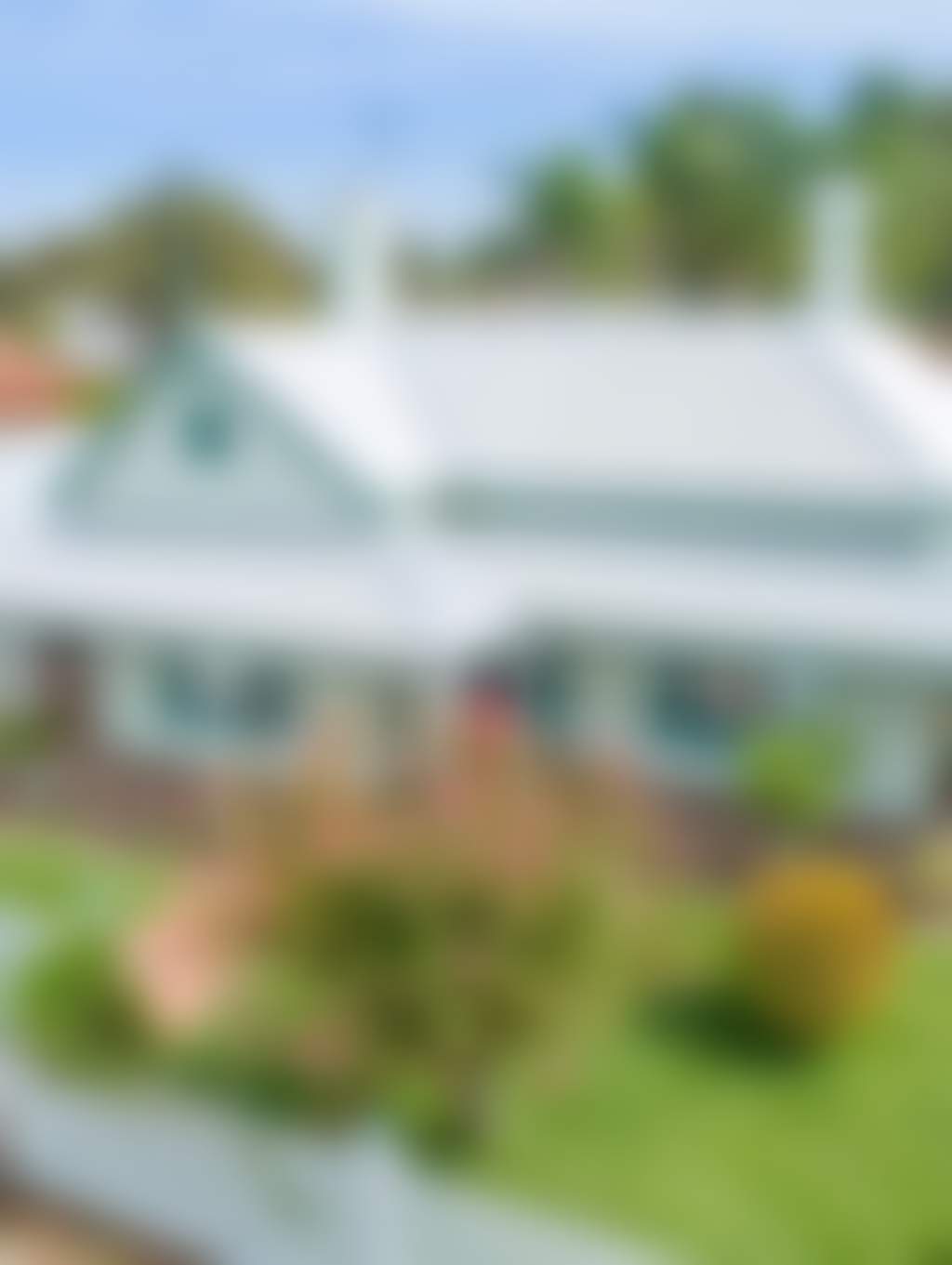 Frontal view of Wandew House and its wrapped patio surrounded by lush greenery