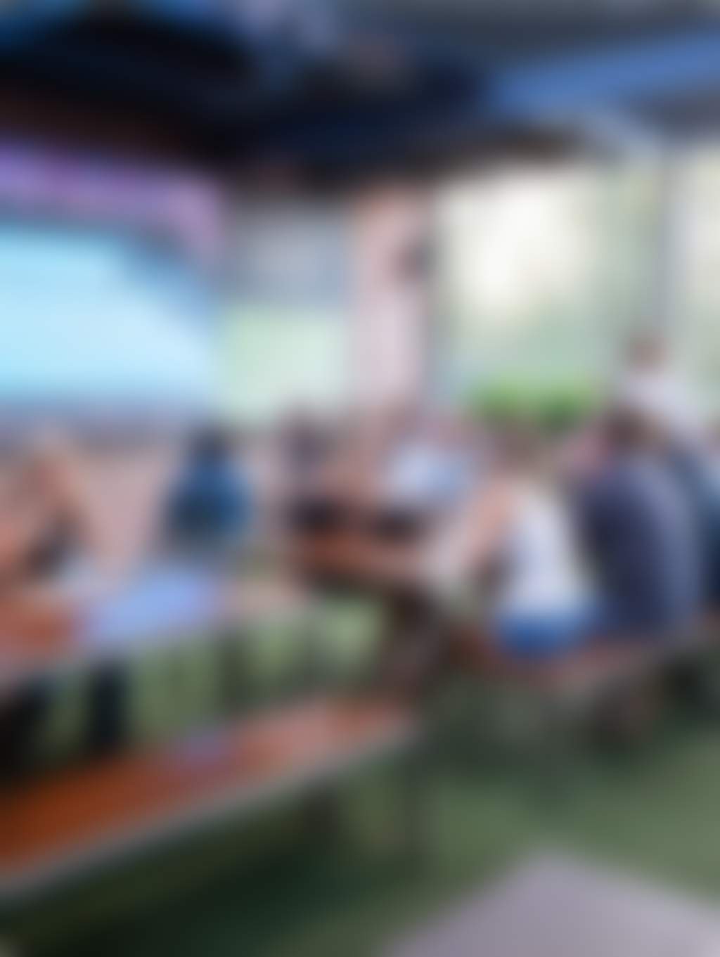 people in an outdoor beer garden watching a big screen TV