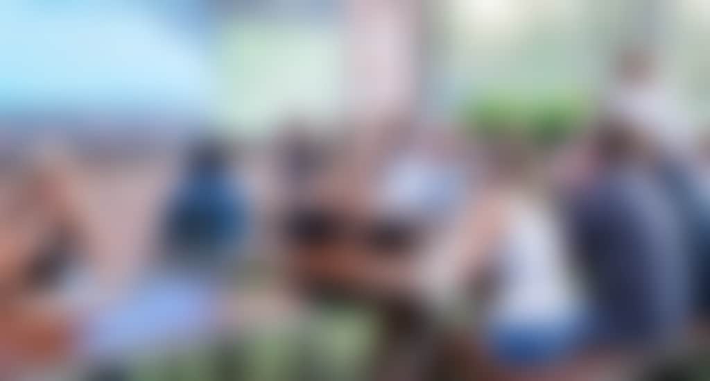 people in an outdoor beer garden watching a big screen TV