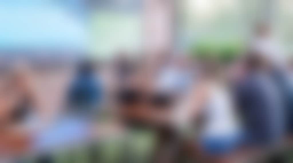 people in an outdoor beer garden watching a big screen TV