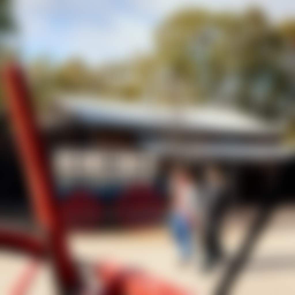 Two visitors walking past a historic red wagon and timber buildings at Port of Echuca