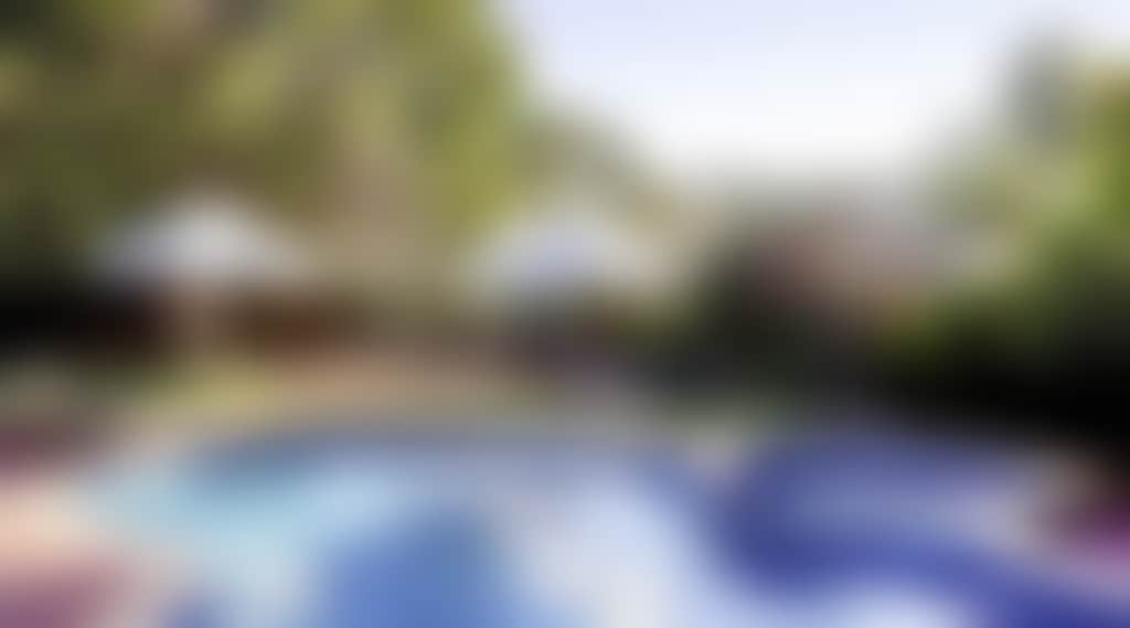 Swimming pool and heated spa surrounded by lush gardens and sun loungers