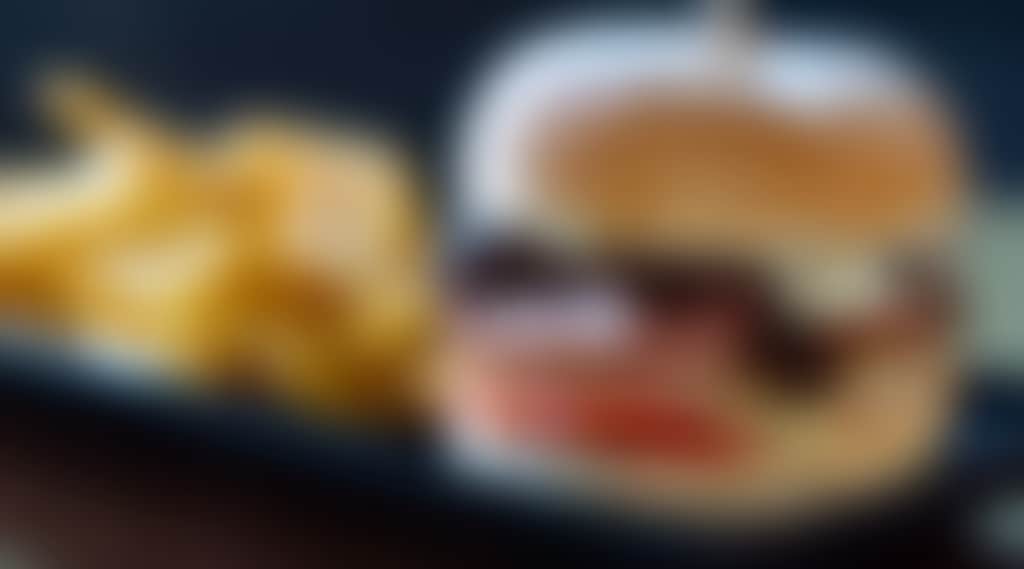 Delicious burger with bacon, tomato and side of chips