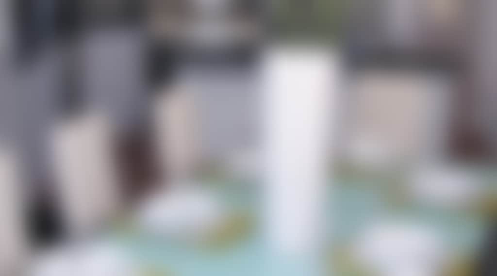 Neatly set dinner table with vase in the centre.