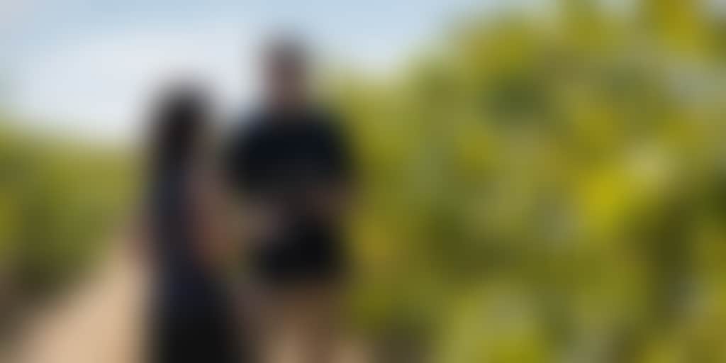 A couple in a vineyard with glasses of wine in hand