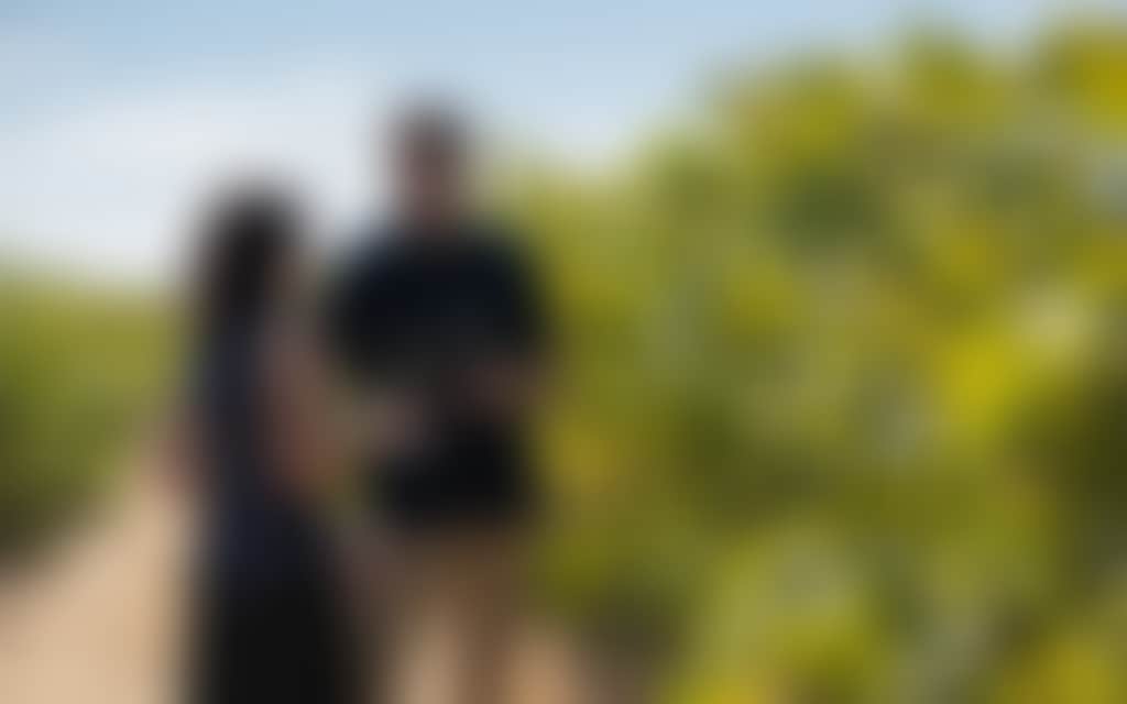 A couple in a vineyard with glasses of wine in hand