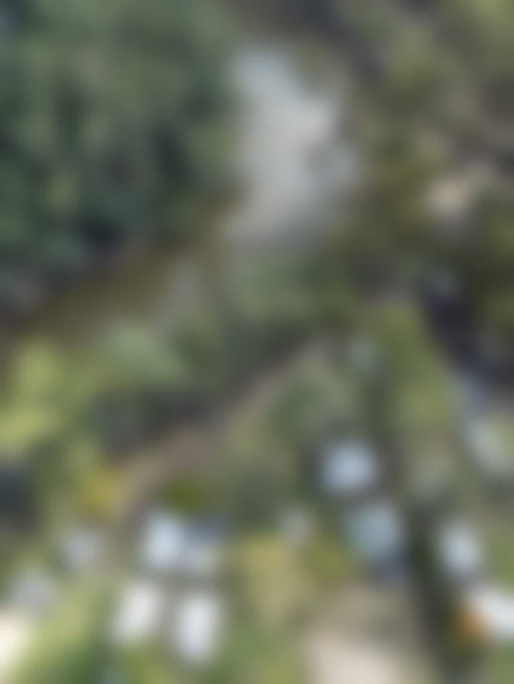 Aerial View of the caravan park beside winding river surrounded by trees