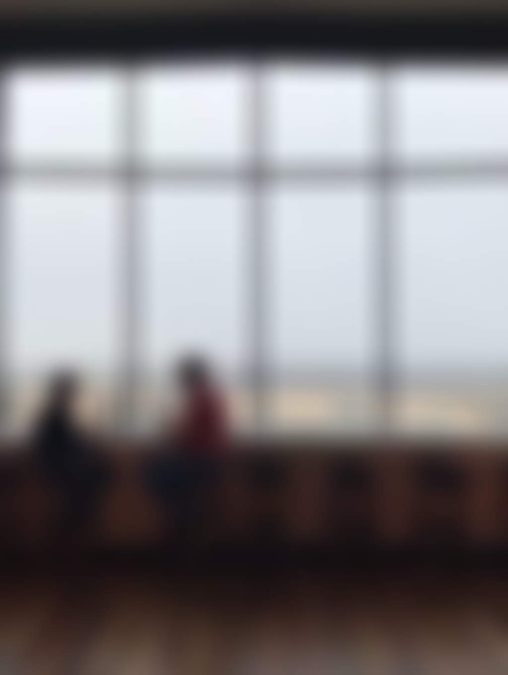 a couple tasting wine in front of a large picture window overlooking a vineyard